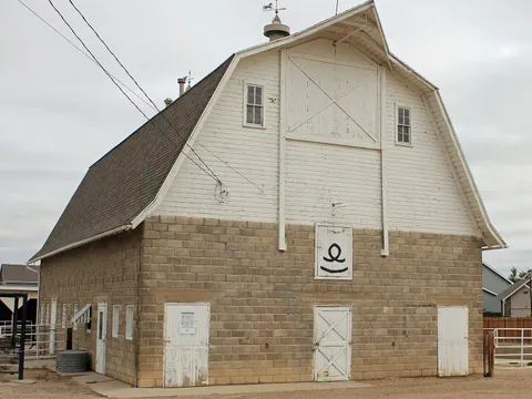 The 1913 Anderson Barn: a white gambrel-roofed loft over a lower storey of grey concrete block, with a horse weathervane on the ridge