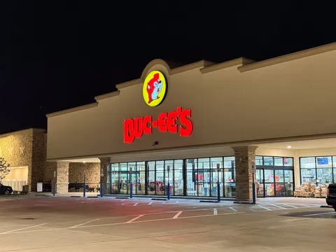 The Buc-ee's storefront lit up at night, the beaver sign over the entrance and an empty car park in front