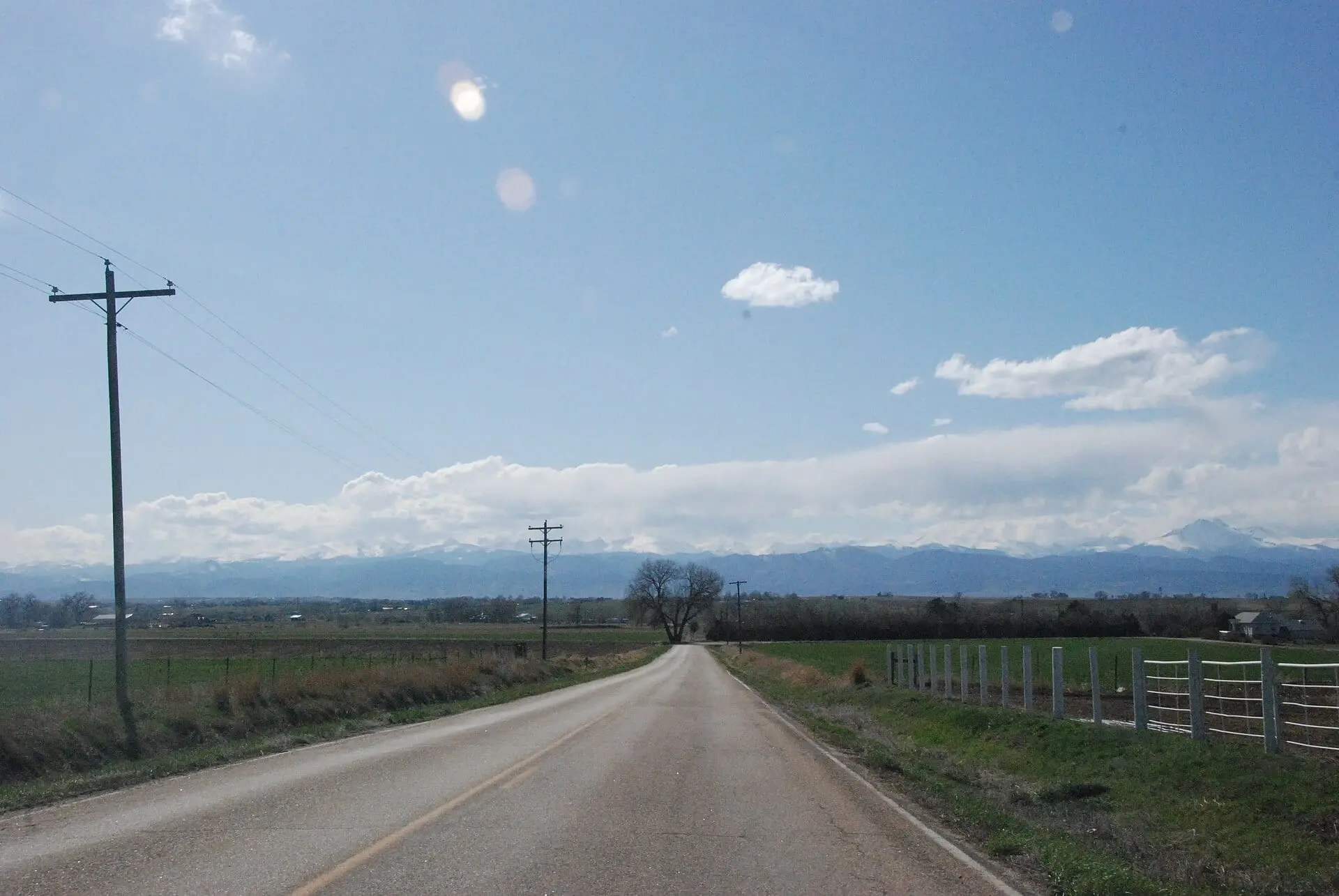 A county road running west out of Johnstown toward the snow-covered Front Range in April