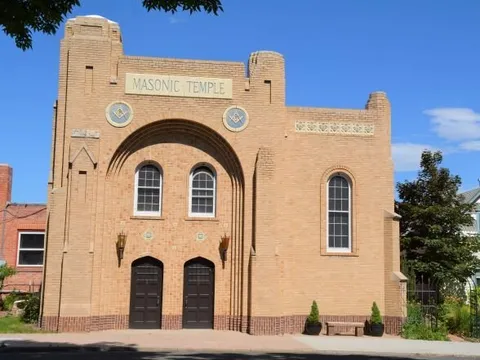 The Masonic Temple, a buff-brick building with a tall arched entrance, twin doors and Masonic emblems set into the facade, now a residence.