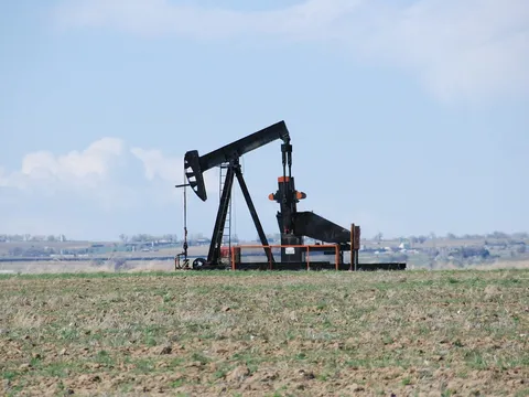 A pumpjack in a bare spring field outside Johnstown, with the plains behind it