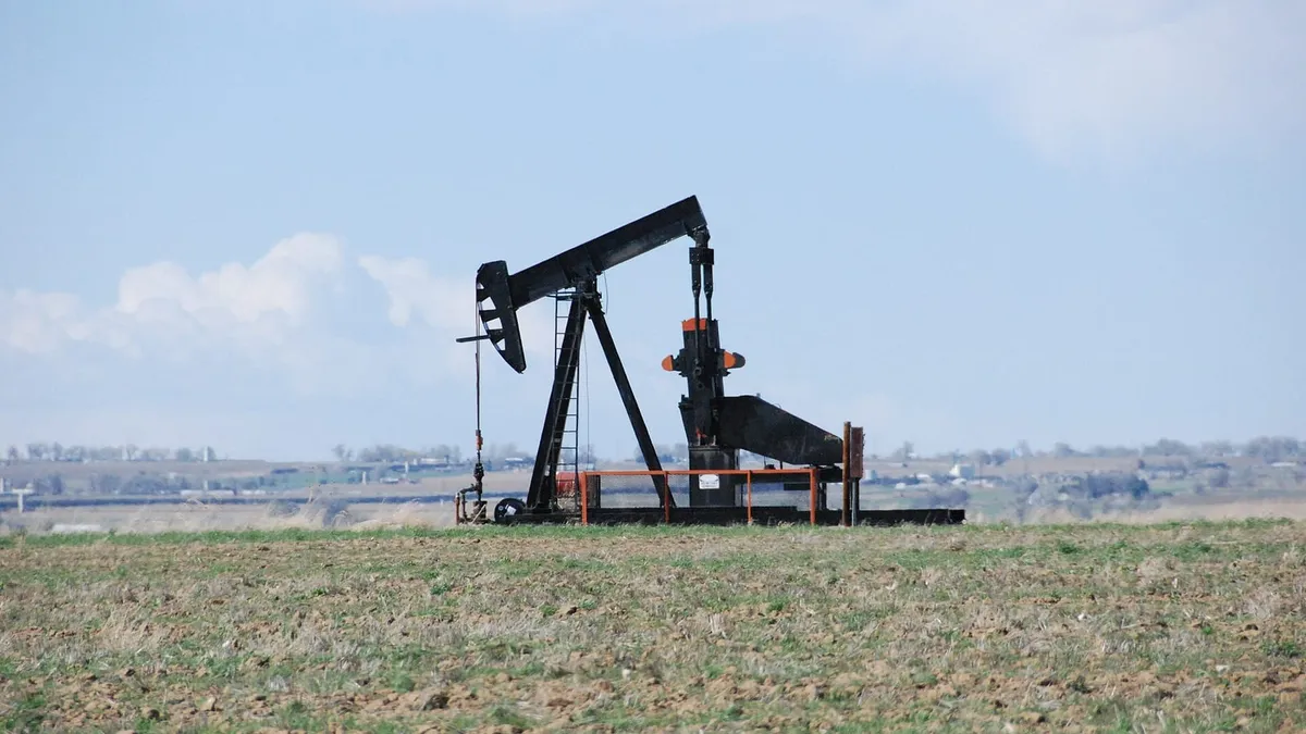 A pumpjack in a bare spring field outside Johnstown, with the plains behind it