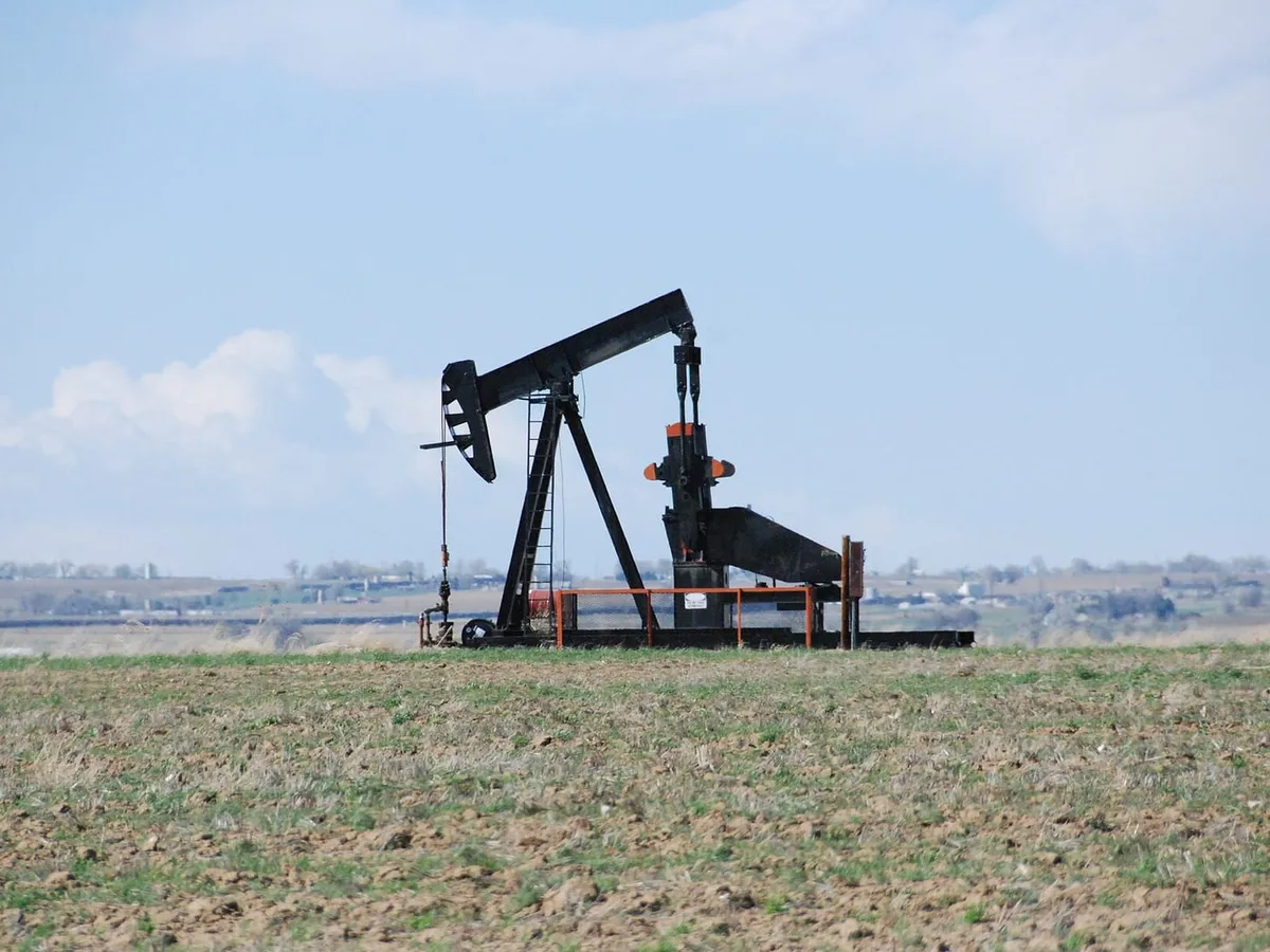 A pumpjack in a bare spring field outside Johnstown, with the plains behind it