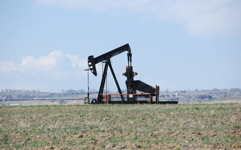 A pumpjack in a bare spring field outside Johnstown, with the plains behind it