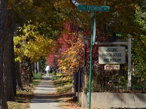 The Charlotte Street sidewalk under autumn trees at Fremont Avenue, beside the Historic Parish House and Museum sign where the walk begins